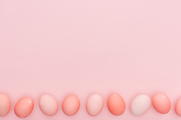 Top view of traditional pastel easter eggs in row isolated on pink with copy space