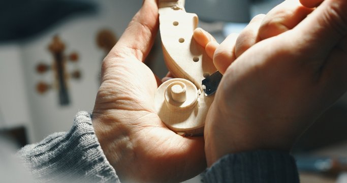 Macro close up of professional master artisan luthier painstaking detailed work on wood violin in a workshop. - Powered by Adobe