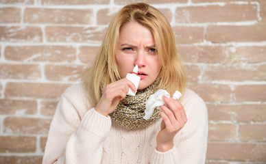 Having the sniffles. Cute woman nursing nasal cold or allergy. Sick woman injecting drops into...