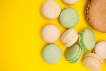 Top view of big caramel macaroon flavour next to little macaroons over yellow background