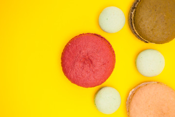 Top view of delicious different macaroons over yellow background