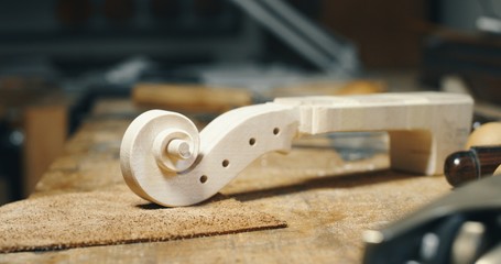 Close up of raw violin with different violin maker work tools on workbench in a workshop of...