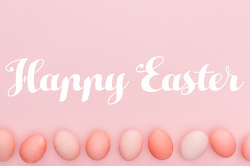 Happy Easter lettering with traditional painted eggs in row isolated on pink