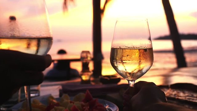 Couple takes two glasses in their hands with white wine against the sunset at the sea. slow motion, 1920x1080