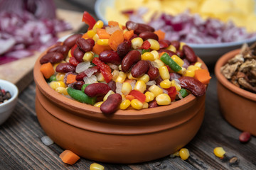 Mixture of vegetables, dried boletus mushrooms, sliced potato, red onion sliced and whole on a cutting board and spices, on old rustic wooden table.