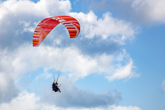 Paraglider flying against the blue sky with clouds