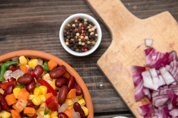 Mixture of vegetables, dried boletus mushrooms, sliced potato, red onion sliced and whole on a cutting board and spices, on old rustic wooden table.