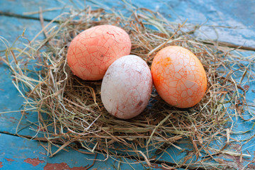 Beautiful Easter multi color egg in straw on wooden background, Easter day concept