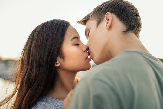 Romantic young couple kissing each other outside in the afternoon