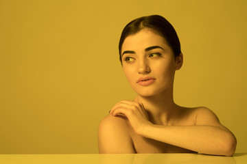 Young beautiful woman face care and skincare on yellow light background