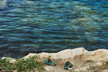 crystal clear blue cool water at the shore of a wild lake in a quarry without people with steep rocky beaches and large boulders on a summer warm day