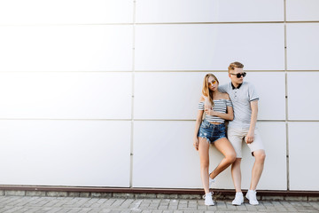 Hipster young loving couple in fashionable sun glasses walking together, embrace each other, hugging and having fun in summer. Urban, love, happiness concept