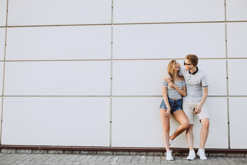 Hipster young loving couple in fashionable sun glasses walking together, embrace each other, hugging and having fun in summer. Urban, love, happiness concept