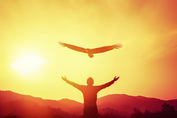 Man raise hand up on top of mountain and sunset sky with eagle bird fly abstract background.