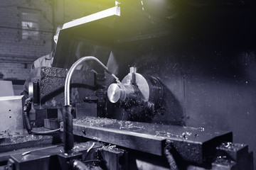 The worker in blue workwear, the operator of the CNC machine, oversees the process and controls it. A man works in a factory with CNC machine