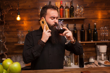 Bearded young batender talking on the phone taking care of his business.
