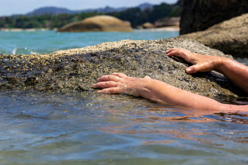 Women's hands are drawn out of the sea, calling for help and trying to grab onto the coastal stone so as not to drown. Close-up. Copy space