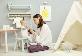 Mother playing with her baby girl in nursery
