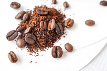 Close up dark roasted coffee beans and coffee ground on white cotton fabric and white filter paper  background in natural light 