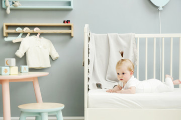 Adorable baby in the white outfit in the nursery