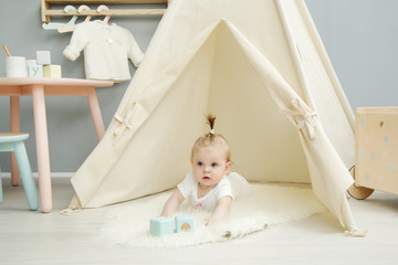 Adorable baby girl laying on the floor in her nursery under the tent © triocean