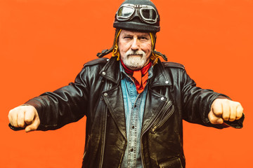 Old biker wearing leather jacket, hat and sunglasses simulating to drive his motorcycle. - Concept...