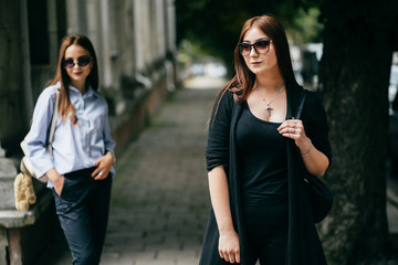 Two young girls in a good mood walking through the city streets