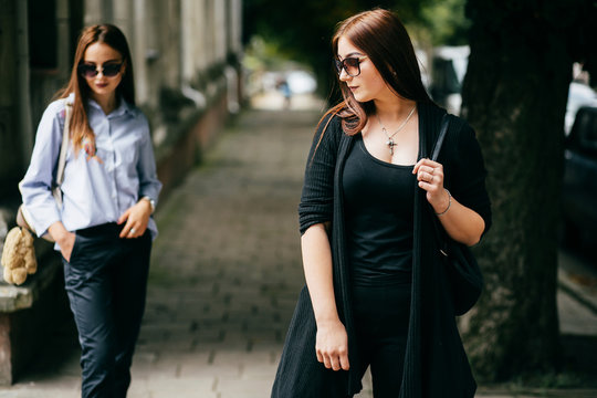 Two young girls in a good mood walking through the city streets