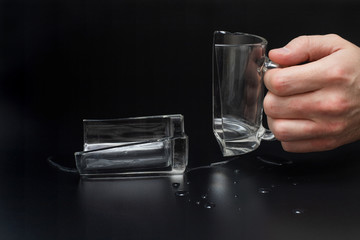 Man holds broken glass cup on black background, incident concept
