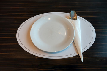 White ceramic dish with spoon,fork and napkin on wooden table
