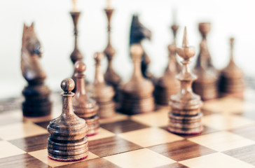 Wooden chess pieces on a chessboard, leadership concept on white background.
