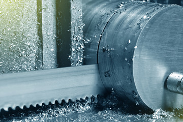 The process of cutting metal with an electric saw in a factory. Electric saw cuts round metal