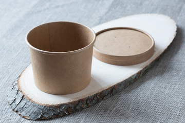 Disposable kraft paper cup on a wooden board.
