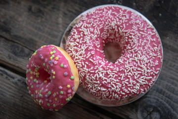Homemade pink glazed donuts on old wooden table