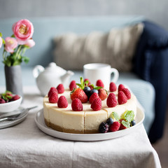 Classic cheesecake with fresh berries on the gray plate at table. Concept of healthy organic summer dessert.