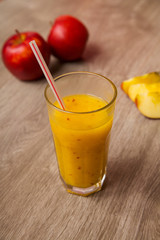 Fresh orange juice with apple in a glass on a wooden table.