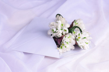White wildflowers in envelope on white fabric background.  Romantic communication background concept mockup.