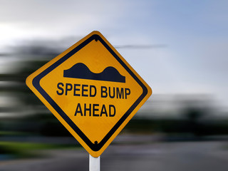 Speed Bump Sign - Yellow Road Traffic Warning Sign, on a Speeding Blurred Background