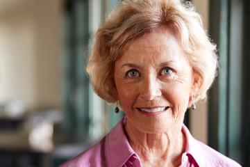 Portrait Of Smiling Senior Woman Sitting In Restaurant
