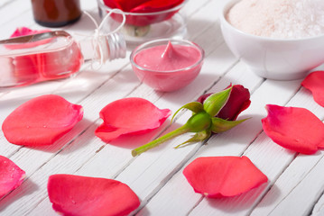 perfume, body care and beauty products with red roses, pink petals on white wood table