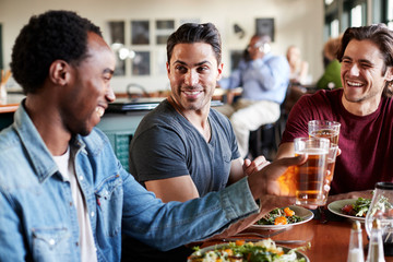 Group Of Male Friends Making A Toast At Meal In Restaurant