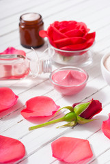 perfume, body care and beauty products with red roses, pink petals on white wood table