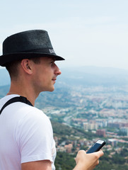 A young guy in a hat with a phone in his hand looks into the distance - 251555241