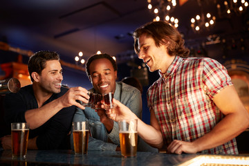 Group Of Male Friends Drinking Shots In Bar Together