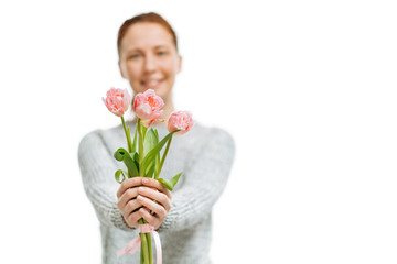 Young beautiful woman gives pink tulips on white background.