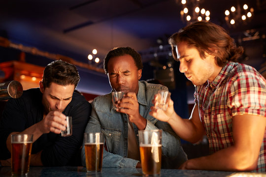 Group Of Male Friends Drinking Shots In Bar Together