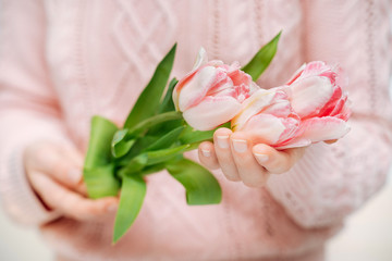 Young woman holding pink tulips on a white background.