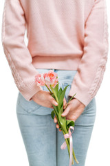 young woman holding of pink tulips behind her back on a white background.