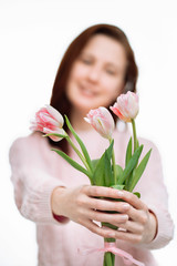 Young beautiful woman gives pink tulips on white background.