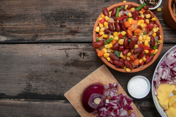 Mixture of vegetables, dried boletus mushrooms, sliced potato, red onion sliced and whole on a cutting board and spices, on old rustic wooden table. With copy space.